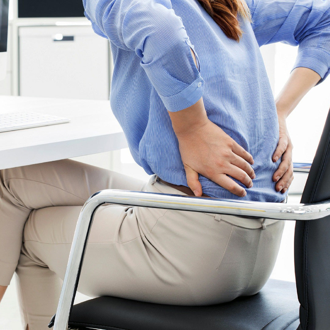 Woman in Office Chair Holding Lower Back from Sciatica